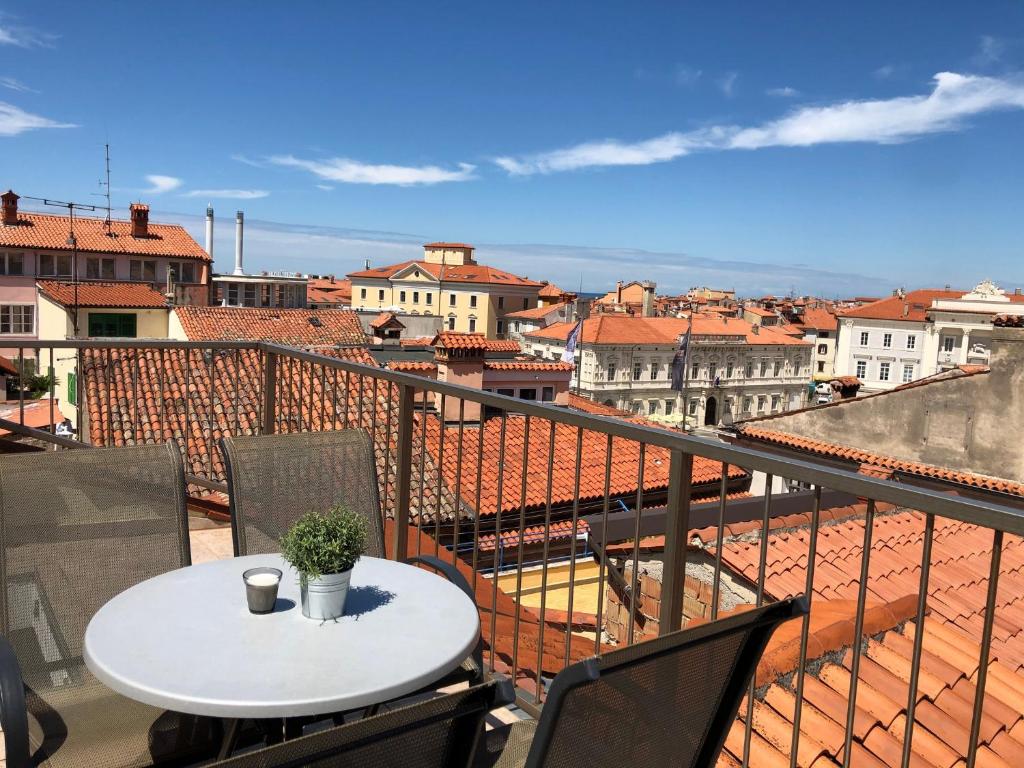 a table on a balcony with a view of a city at Tartini Square House FERGO in Piran