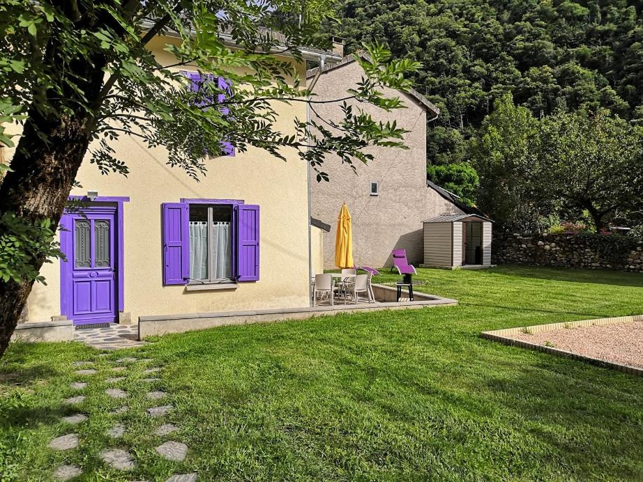 una casa con puertas moradas y un patio con césped en La glycine, en Sinsat