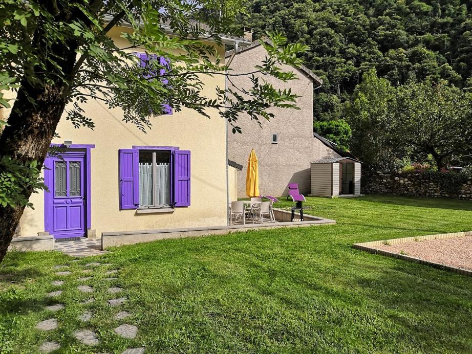 une maison avec des portes violettes et une cour avec de l'herbe dans l'établissement La glycine, à Sinsat