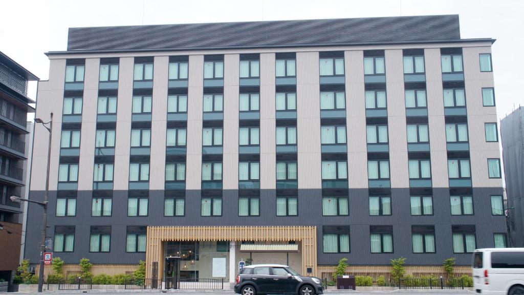 um grande edifício com carros estacionados em frente em ホテルアベストグランデ京都清水 em Quioto