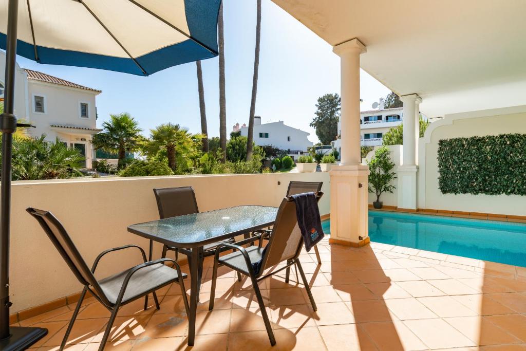 un patio con mesa y sillas y una piscina en Vale de Lobo by Intiholidays, en Vale do Lobo