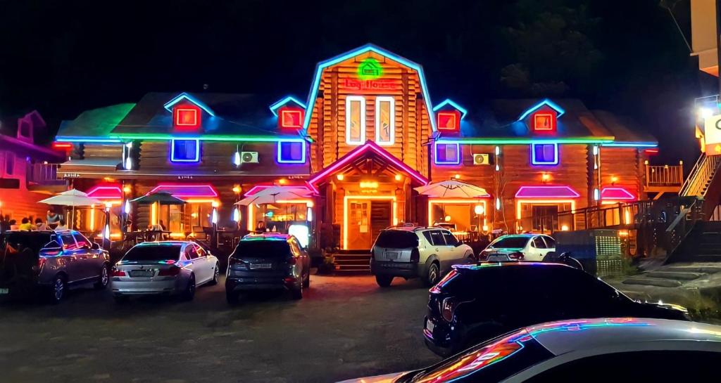 Muju Log House Pension في Muju: منزل مضاء فيه سيارات متوقفة أمامه