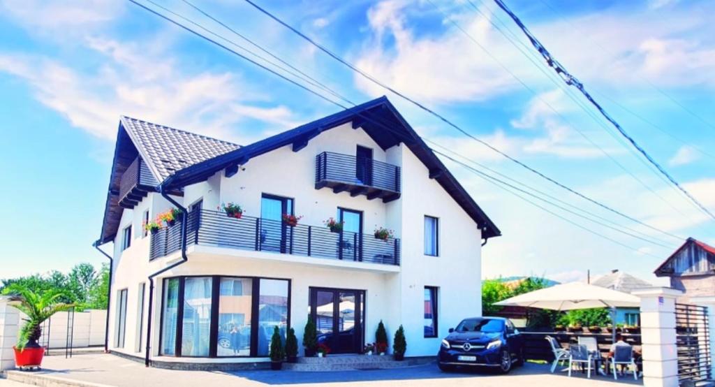 une maison blanche avec une voiture garée devant elle dans l'établissement Regal Guest House, à Sighetu Marmaţiei