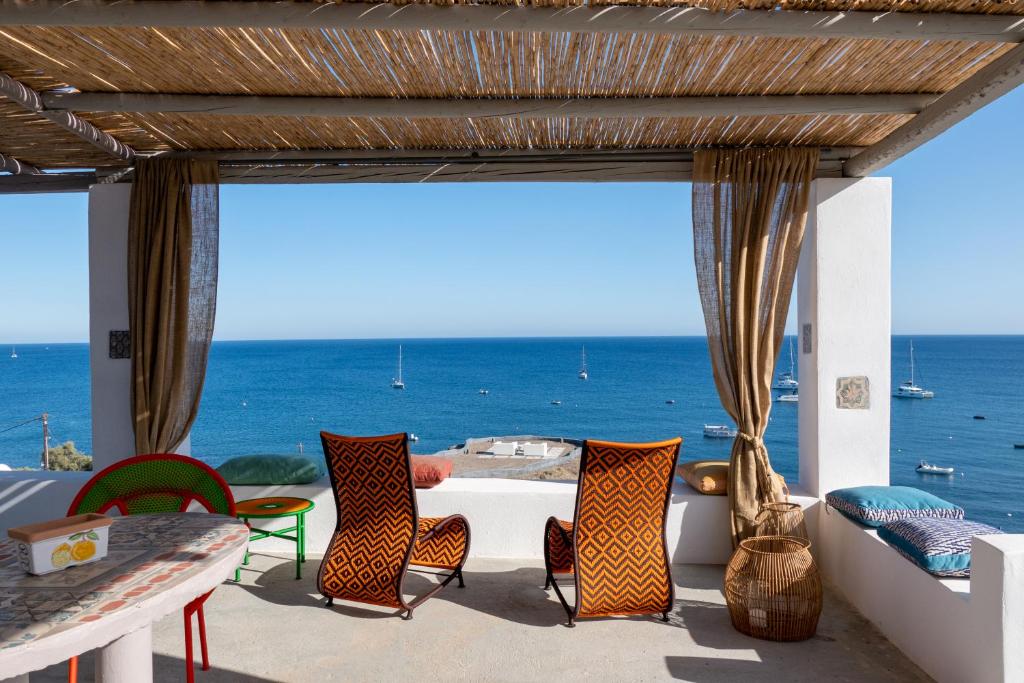 een patio met een tafel en stoelen en de oceaan bij Le Grand Blue Villa in Akrotiri