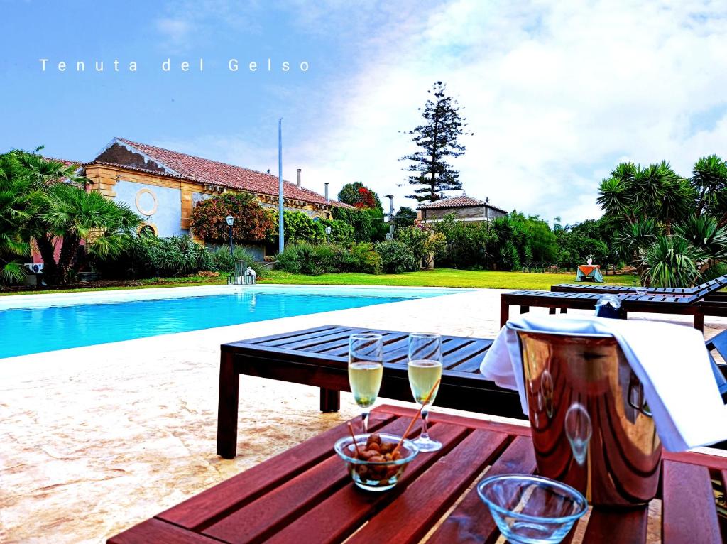 a table with two glasses of wine on it next to a pool at Tenuta del Gelso in Catania