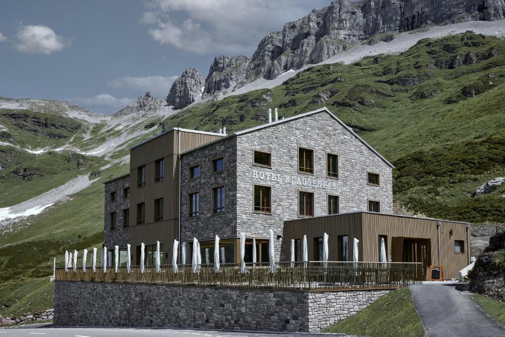 a building on a hill with a mountain at Hotel Klausenpass in Unterschächen