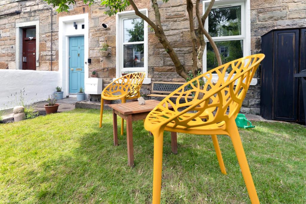 two yellow chairs and a table in a yard at Cozy with Character Cochrane Cottage at Leith Links Park in Edinburgh