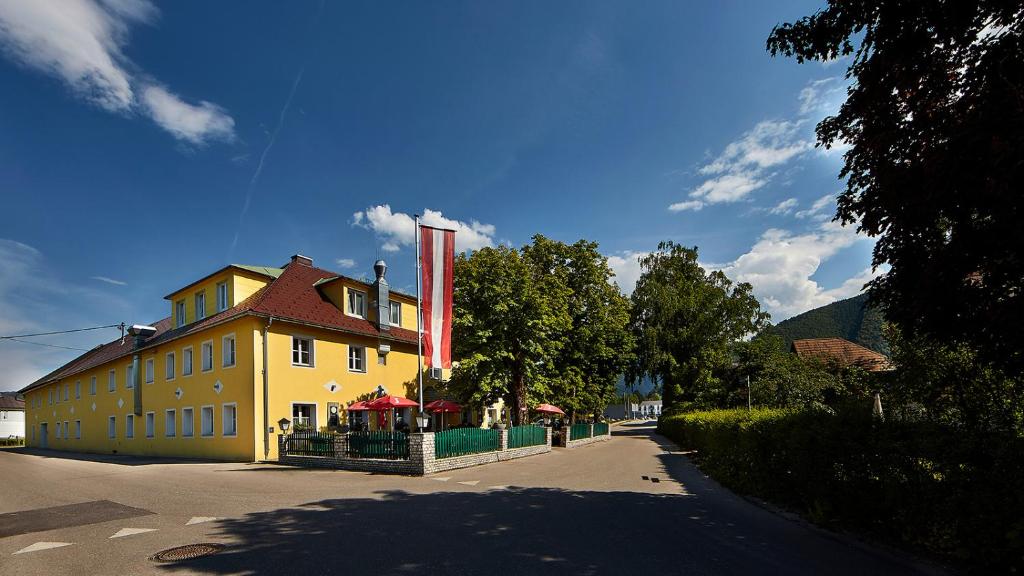 ein großes gelbes Gebäude mit einer roten Flagge. in der Unterkunft Landgasthof Klausner in Molln