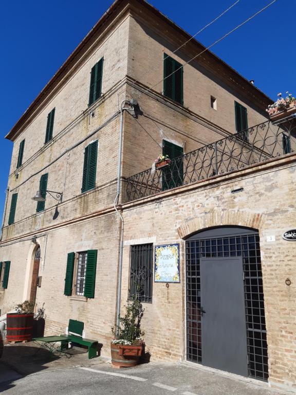 ein großes Backsteingebäude mit einer Tür und einem Balkon in der Unterkunft Palazzo Tuemi in Castelplanio