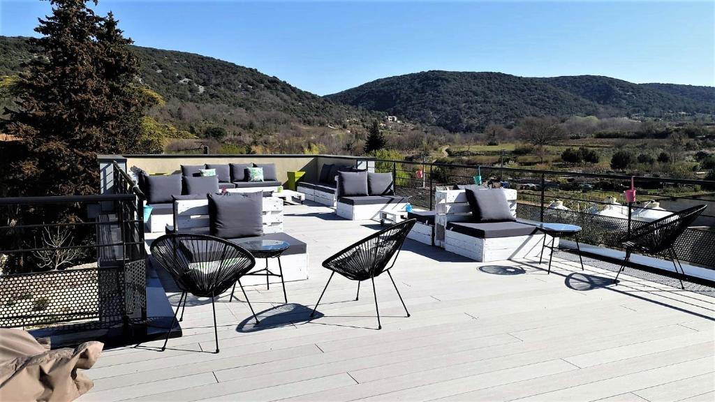 a patio with chairs and tables with mountains in the background at Hostel les Terrasses du Roc in Saint-André-de-Roquepertuis