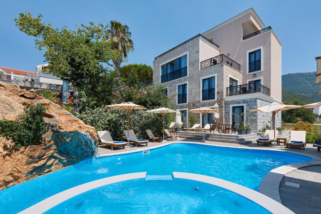 a villa with a swimming pool in front of a building at Moderna Luxury Apartments with HEATED pool in Tivat