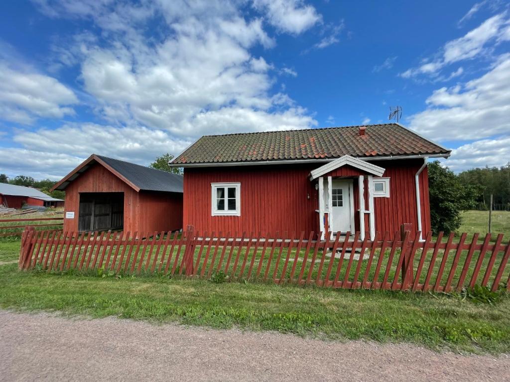 a red house with a fence in front of it at Ekhaga, Hultåkra in Mariannelund