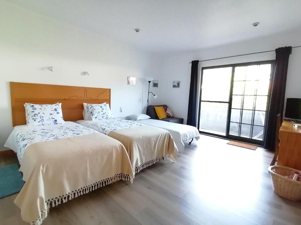 two beds in a room with a large window at Quinta do Areeiro in Horta