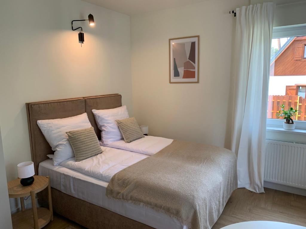sypialnia z łóżkiem z białą pościelą i oknem w obiekcie Na Wczasowej - Apartamenty w mieście Międzywodzie