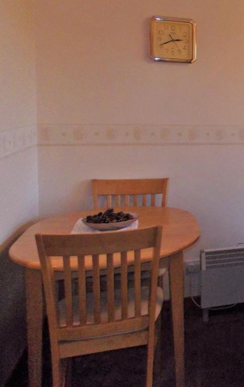 a wooden table with two chairs and a clock on the wall at Riverside in Tarbert