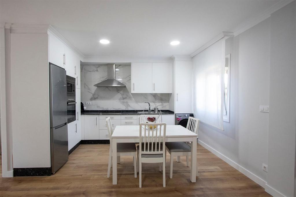 biała kuchnia z białym stołem i krzesłami w obiekcie Precioso apartamento en Marín. w mieście Marín