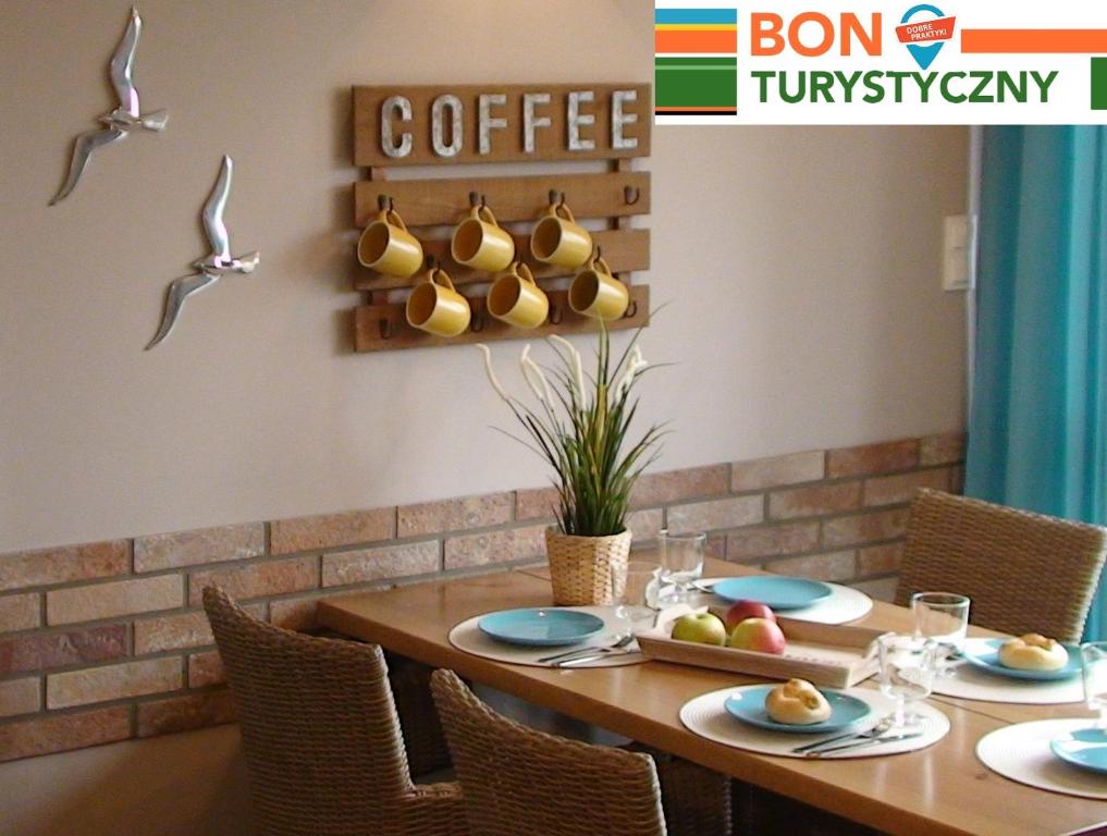 a dining room with a table with chairs and a coffee sign at Apartament Comfort in Trzęsacz