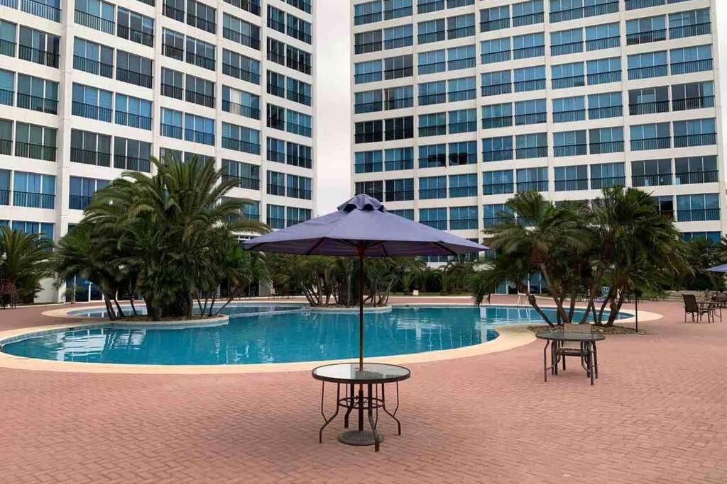 a pool with tables and an umbrella in front of two buildings at Suite de lujo Punta Centinela in La Libertad