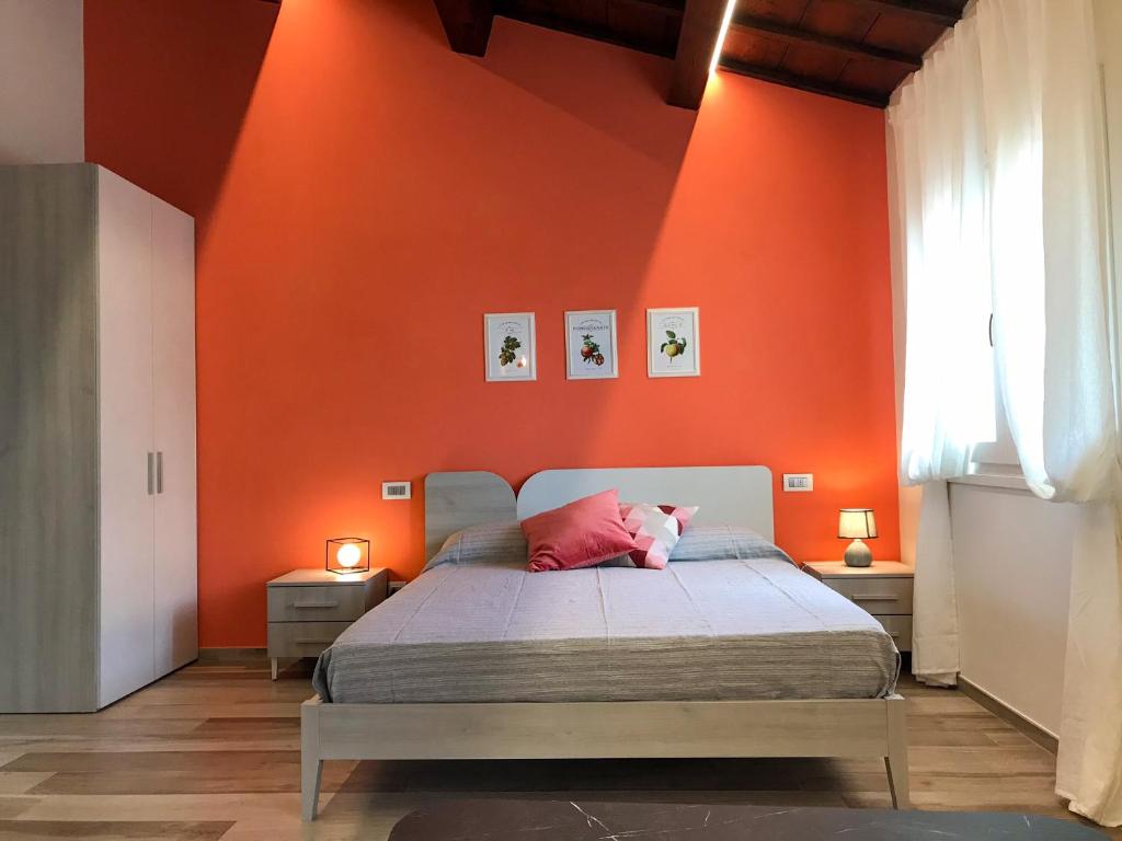 a bedroom with orange walls and a bed with a pink pillow at Podere Baratta agriturismo e cantina in Collinello