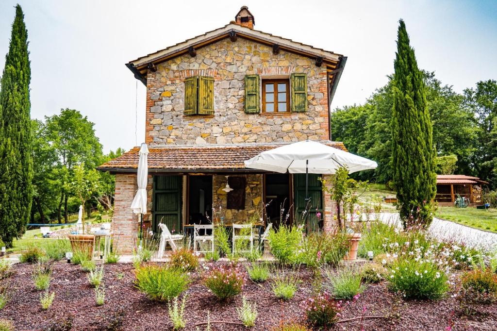 una casa de piedra con una sombrilla en un jardín en Tenuta Gambit Agriturismo Umbria, en Monteleone dʼOrvieto