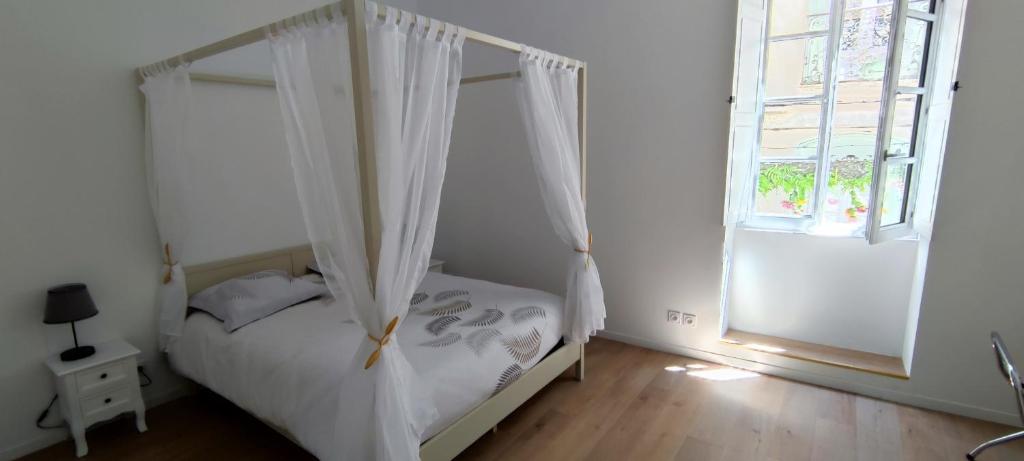 ein Schlafzimmer mit einem Himmelbett und einem Fenster in der Unterkunft Soleil Roi - immeuble du 16e siècle en plein coeur de Béziers in Béziers