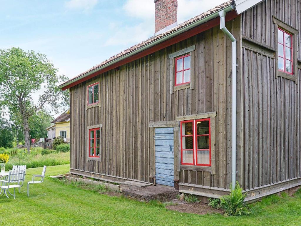 ein Holzhaus mit roten Fenstern auf einem Hof in der Unterkunft 4 person holiday home in N SSJ in Nässjö