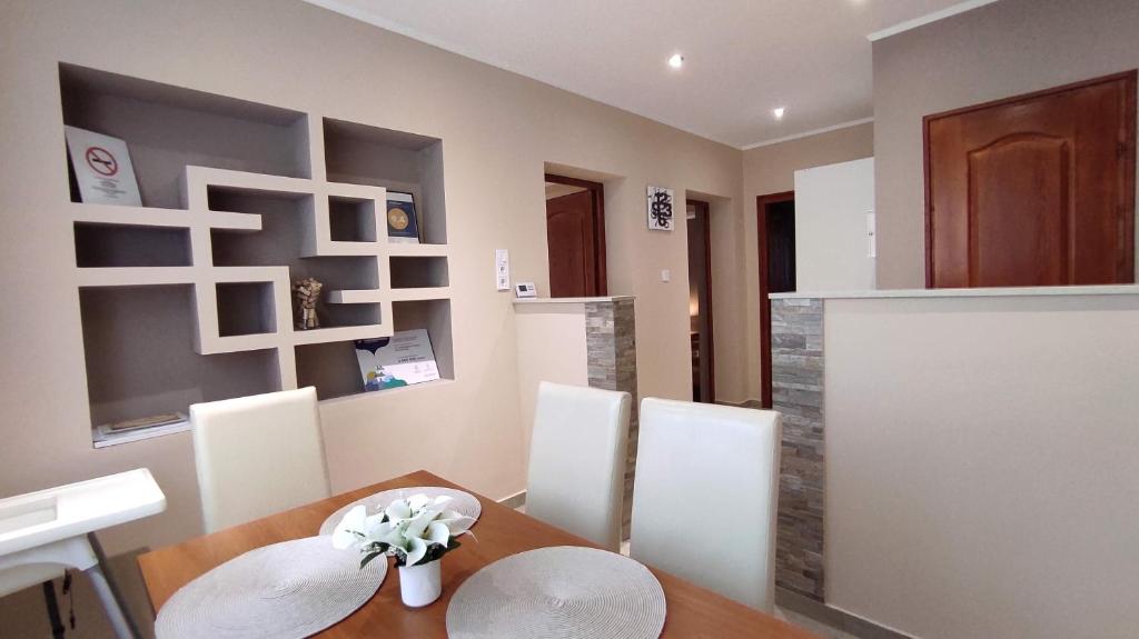 a dining room with a wooden table and white chairs at Lux Apartman Velence in Velence