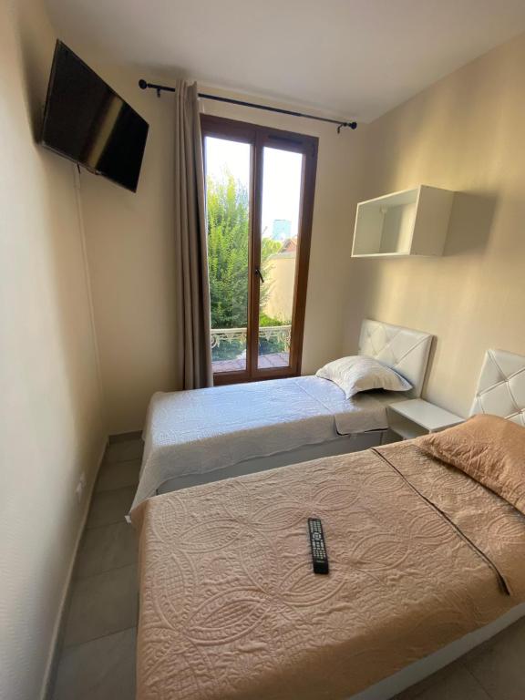 two beds in a room with a window at RENT APPART - La Garenne Colombes in La Garenne-Colombes