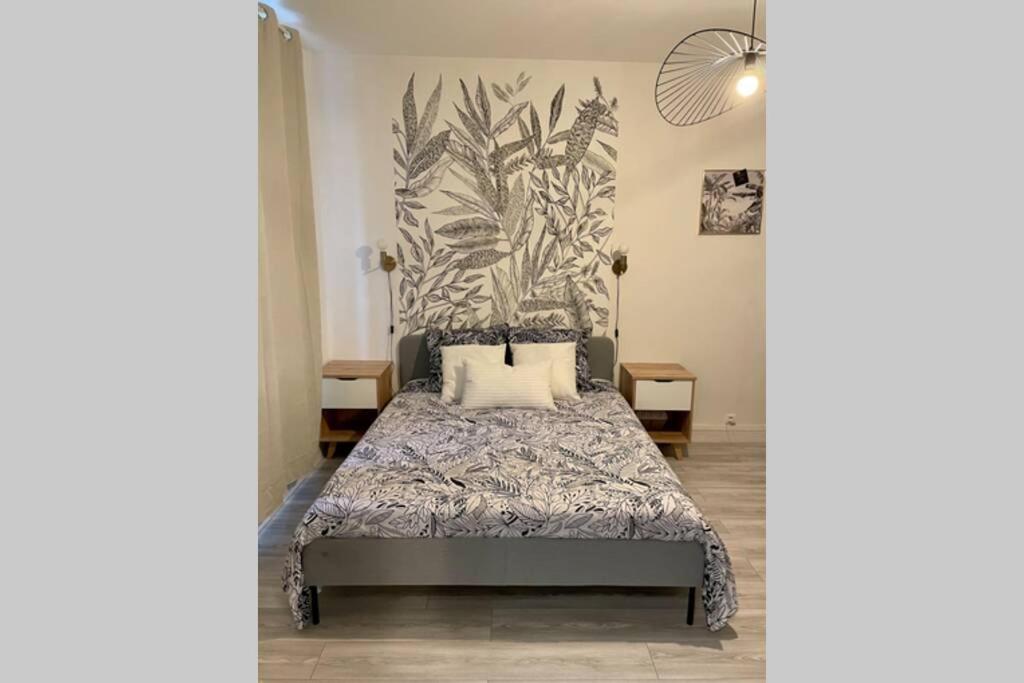 um quarto com uma cama com um mural de plantas na parede em Appartement studio avec terrasse et jardin privés em Boulogne-sur-Mer