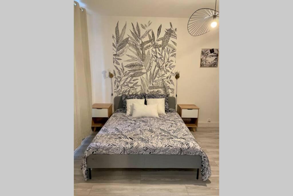 une chambre avec un lit avec une fresque végétale sur le mur dans l'établissement Appartement studio avec terrasse et jardin privés, à Boulogne-sur-Mer