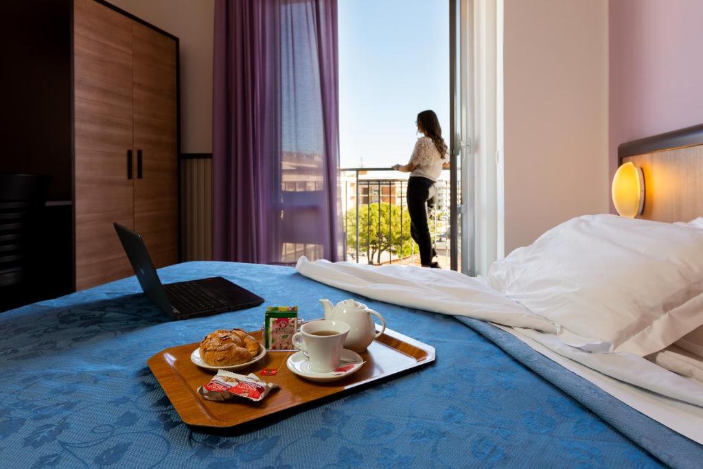 a bed with a tray of food and a laptop on it at Hotel Belvedere in Porto SantʼElpidio