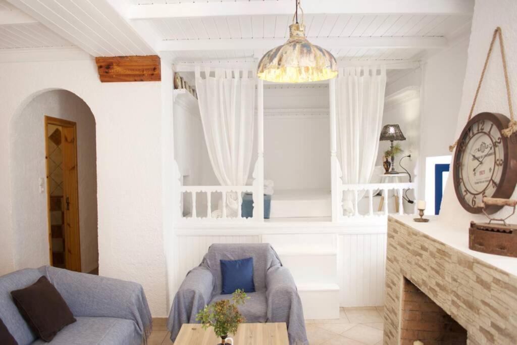 a living room with a couch and a chair and a clock at Unique & Restored Karpathian House in Karpathos