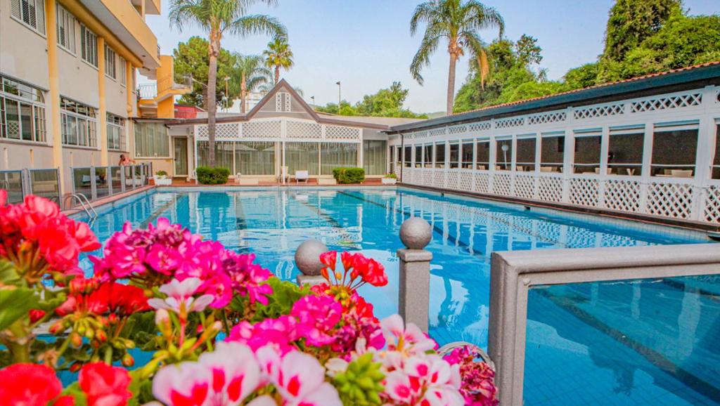 une piscine dans un hôtel avec des fleurs roses dans l'établissement Hotel I Gigli, à Nola