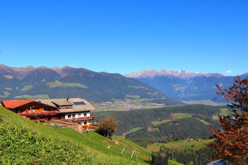 una casa en una colina con montañas en el fondo en Berggasthof Häusler, en San Lorenzo di Sebato