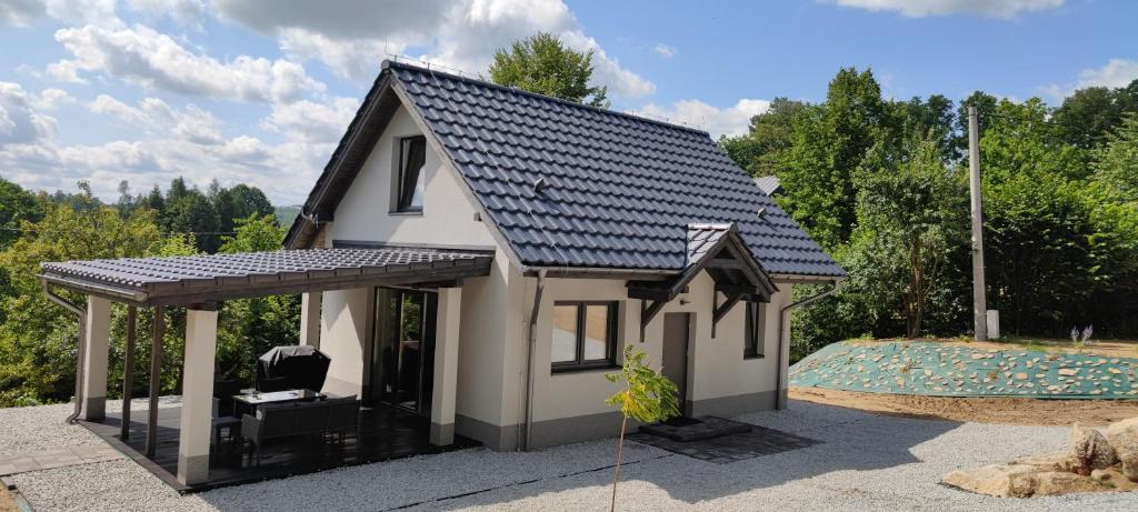 une petite maison blanche avec un toit noir dans l'établissement Przystań pod Witoszą, à Staniszów