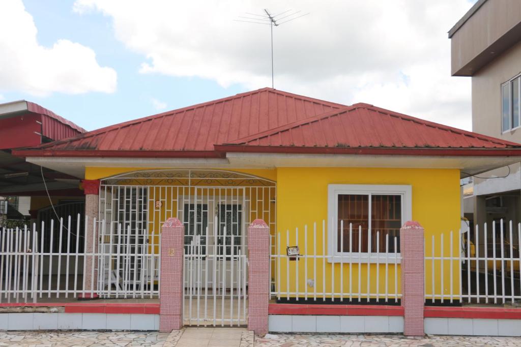 una pequeña casa amarilla con techo rojo en Compleet vrijstaand woonhuis Paramaribo, en Paramaribo
