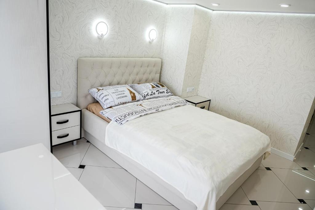 ein weißes Schlafzimmer mit einem Bett und einem Spiegel in der Unterkunft Чарівна квартира-студія на мансардному поверсі! in Ternopil