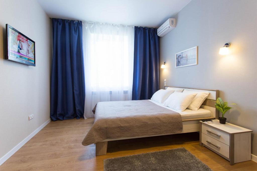 a bedroom with a bed and a window with blue curtains at New studio, metro Pushkinska and Universytet - Chernyshevska str. 95-3 in Kharkiv