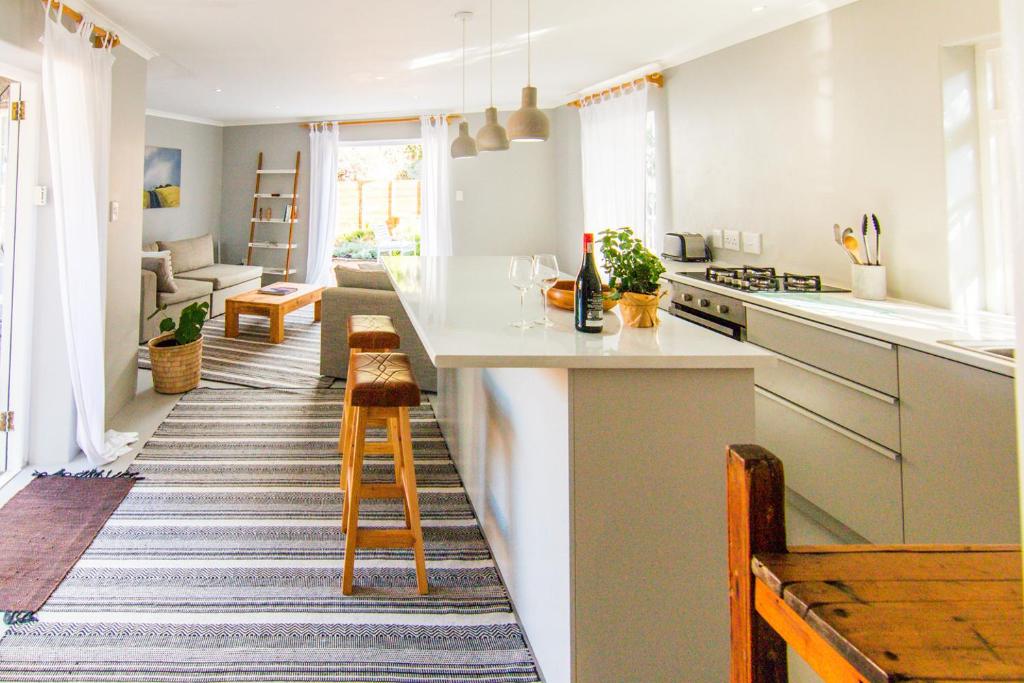 a kitchen with white countertops and a living room at Spacious and light Kalk Bay Garden Apartment in Kalk Bay