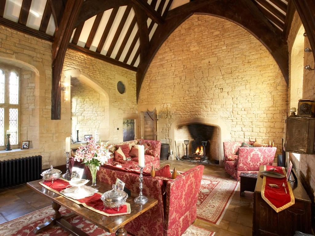 a living room with a red couch and a fireplace at Abbots Grange Manor House in Broadway