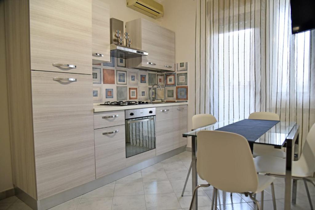 uma cozinha com uma mesa, cadeiras e um fogão em Casa Vacanze le Palme Netine em Noto