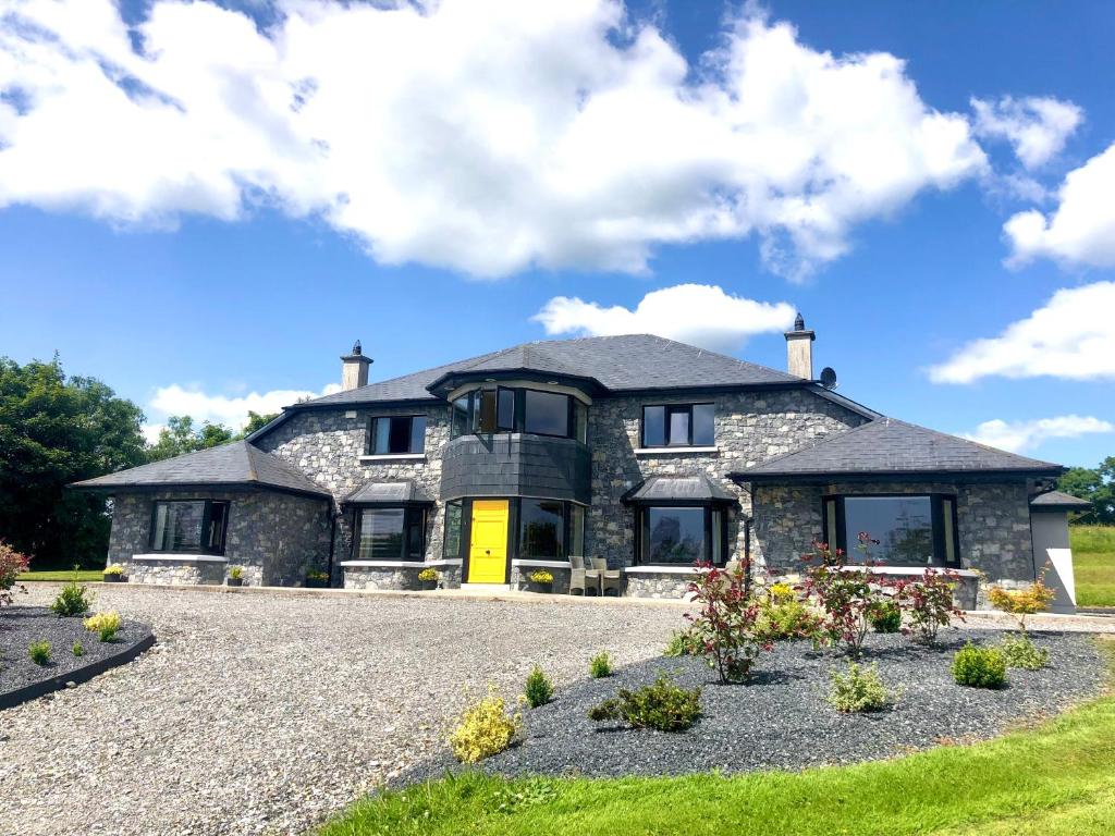 una grande casa in pietra con una porta gialla di Ballyhourode House a Dún ar Aill