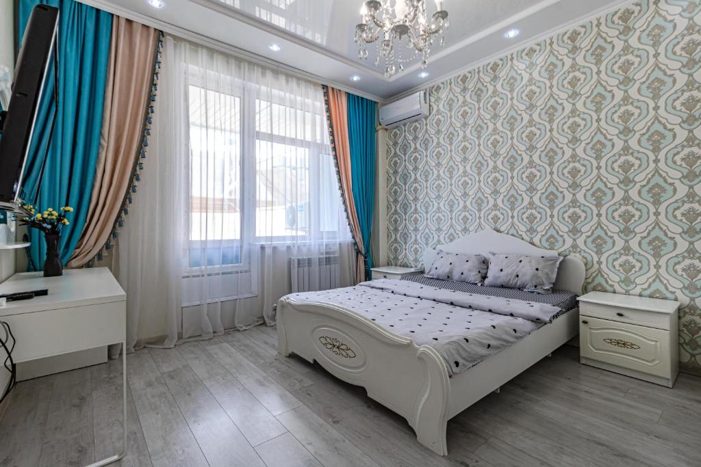 een slaapkamer met een wit bed en een kroonluchter bij Apartment with Terrace-Апартаменты с террасой, ЭКСПО, Mega Silky Way in Astana