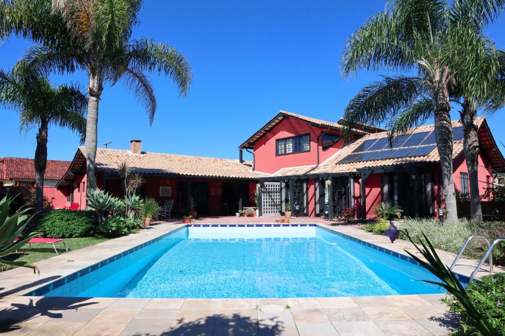 uma piscina em frente a uma casa com palmeiras em Janela de Marcia Bed and Breakfast em Florianópolis