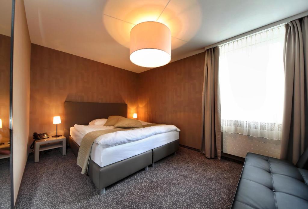 um quarto com uma cama e uma janela grande em Hôtel la Suite em Payerne