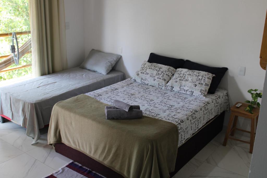 a bedroom with two beds and a window with a table at Flats Maui in Barra Grande