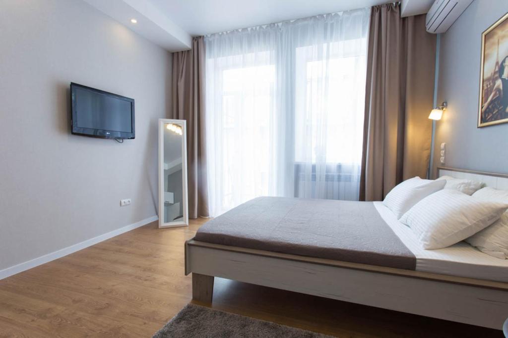 a bedroom with a bed and a tv on a wall at Studio LUX beside metro Universytet, Pushkinska - Chernyshevska str. 95-5 in Kharkiv