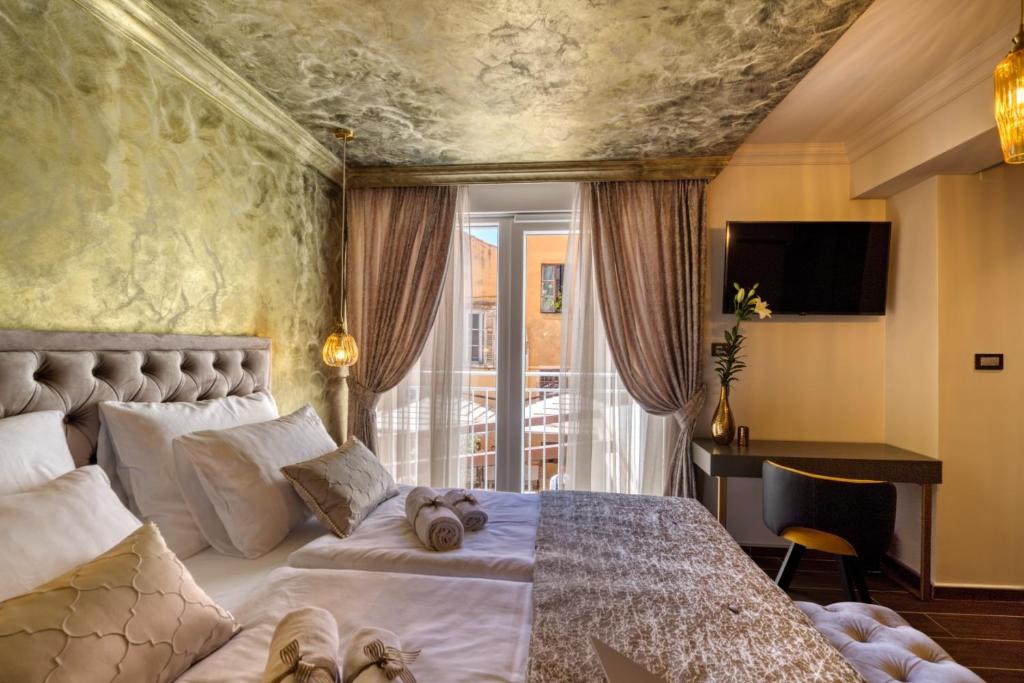 ein Schlafzimmer mit einem Bett, einem Schreibtisch und einem Fenster in der Unterkunft Luxury Rooms VINDEMIÆ in Zadar