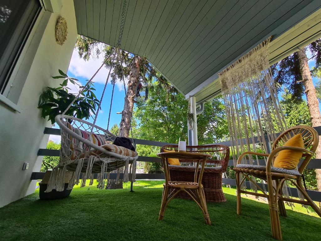 una hamaca en un porche con sillas y mesa en Világos Kert Balatonvilágos Chill House, en Balatonvilágos