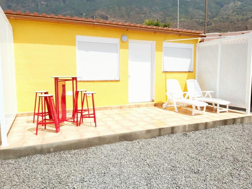 un patio con sillas y mesas y una casa amarilla en Loft Con Encanto en Frontera